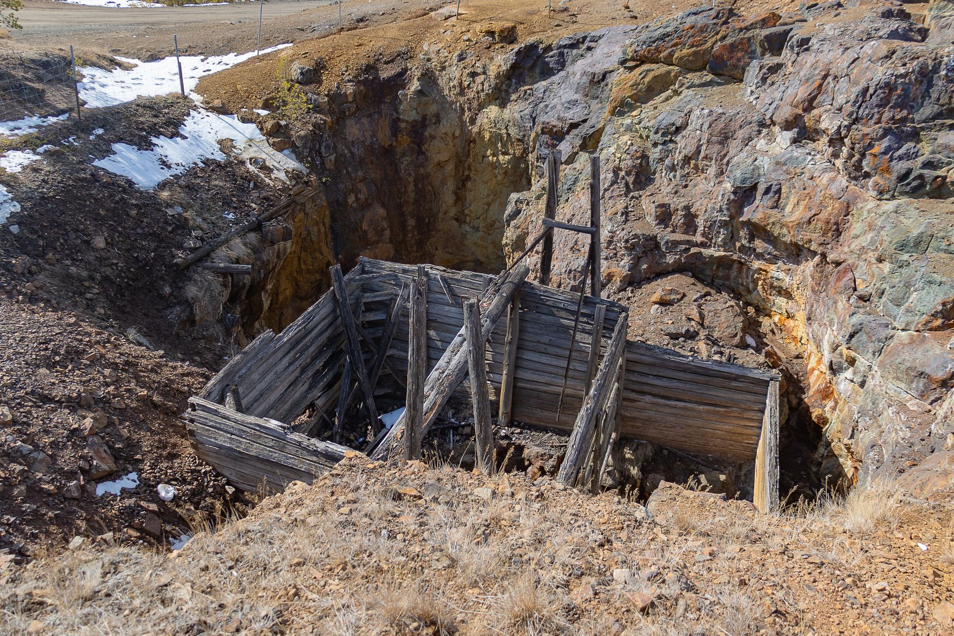 An abandoned wooden mine entrance set in a rural rocky landscape
