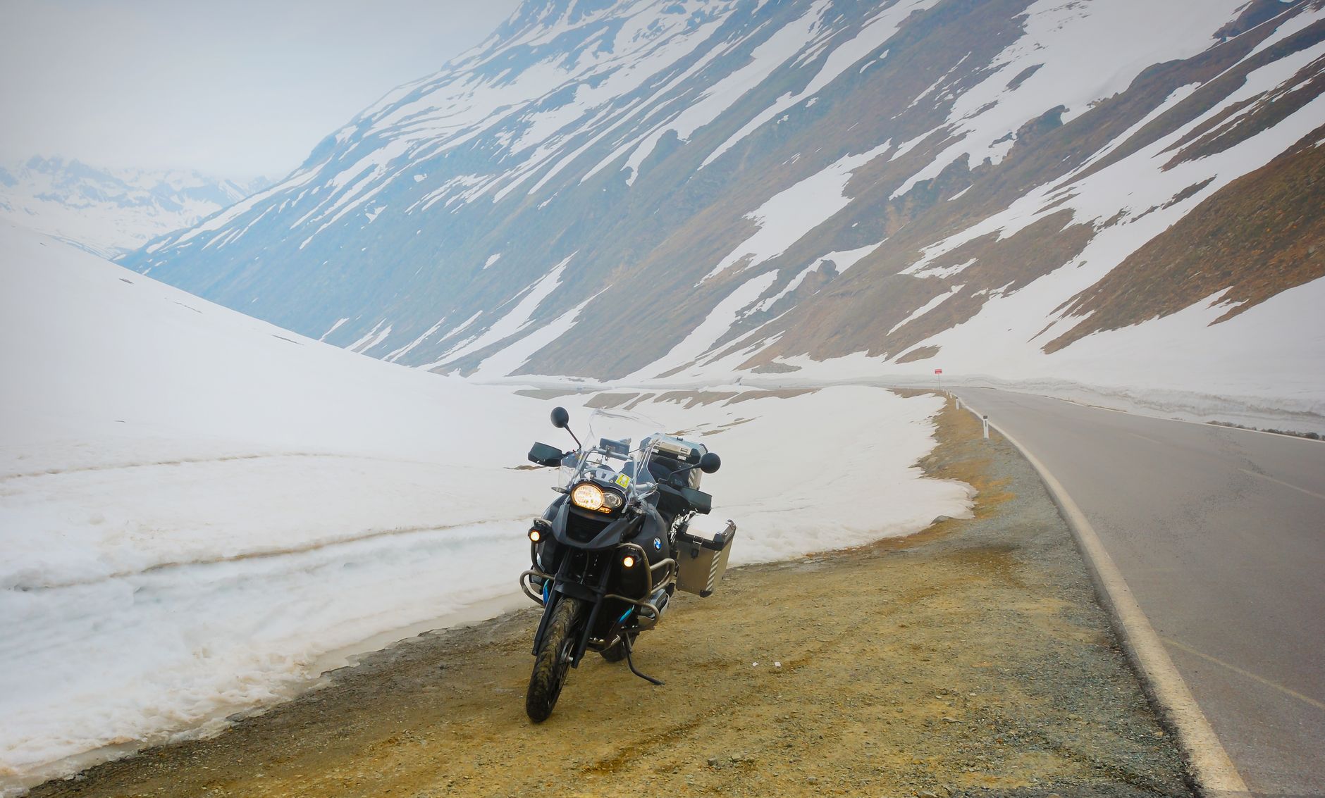 Adventure motorcycle parked by a snowy mountain road