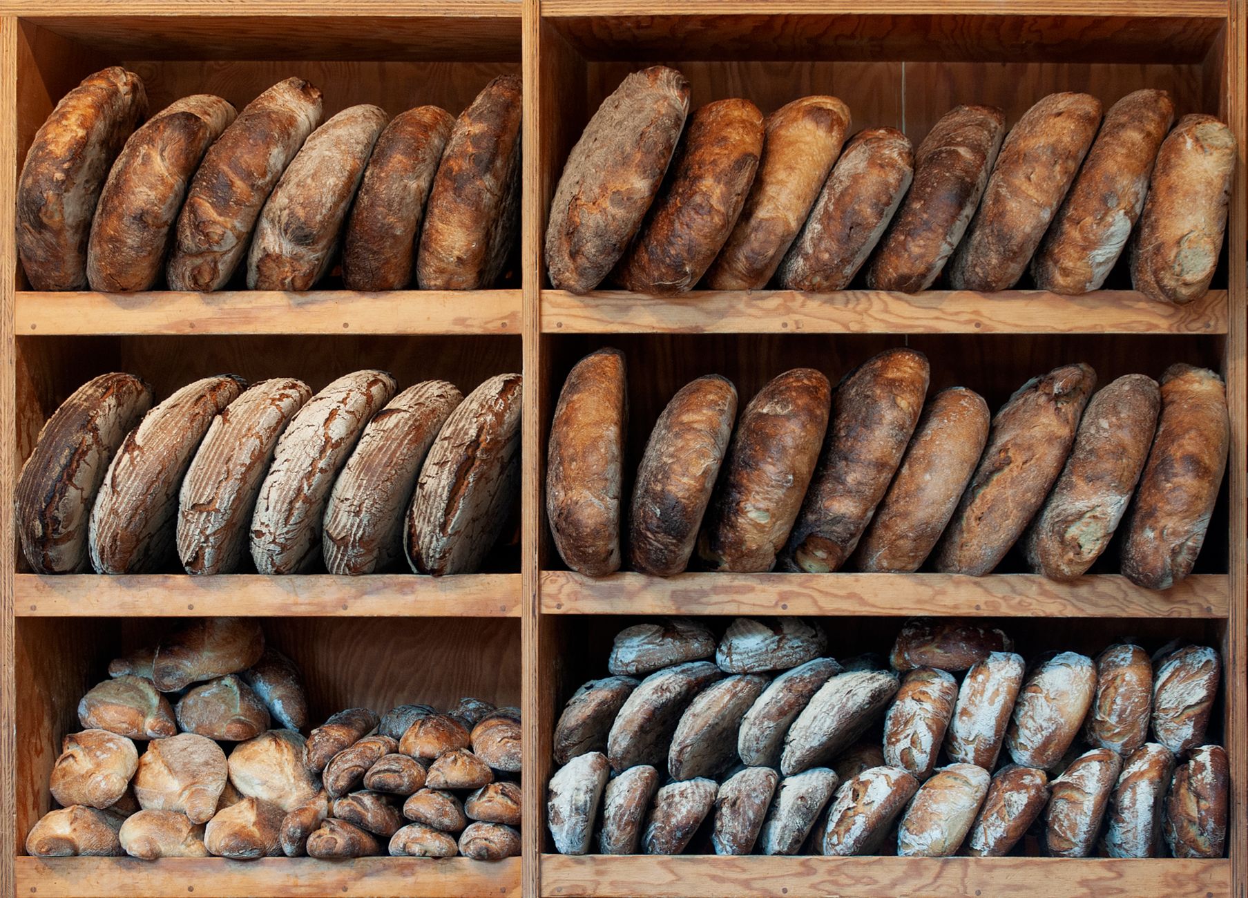 A variety of artisanal breads neatly arranged on wooden shelves