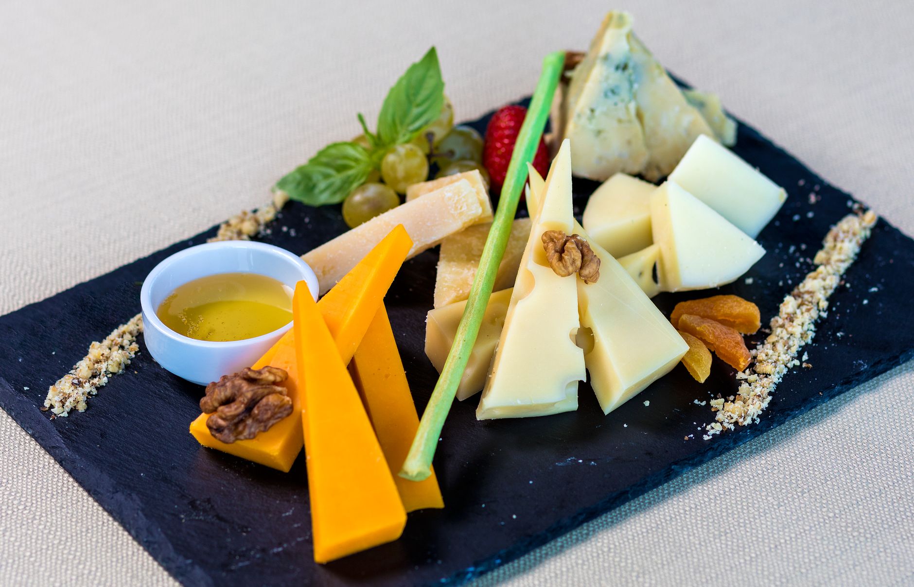 A close-up of an assorted cheese board featuring various cheeses and fruits