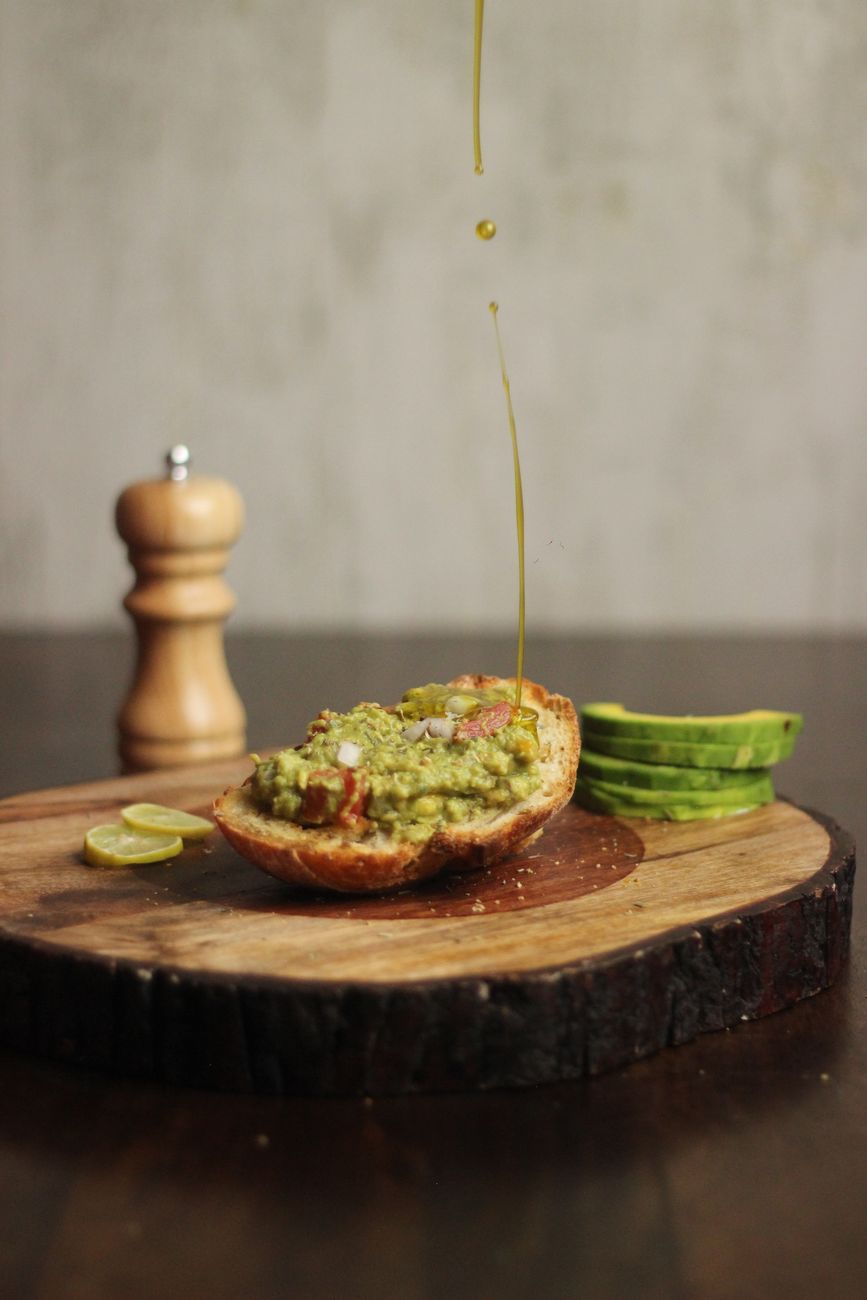Close-up of an avocado toast with a drizzle of olive oil, on a rustic surface