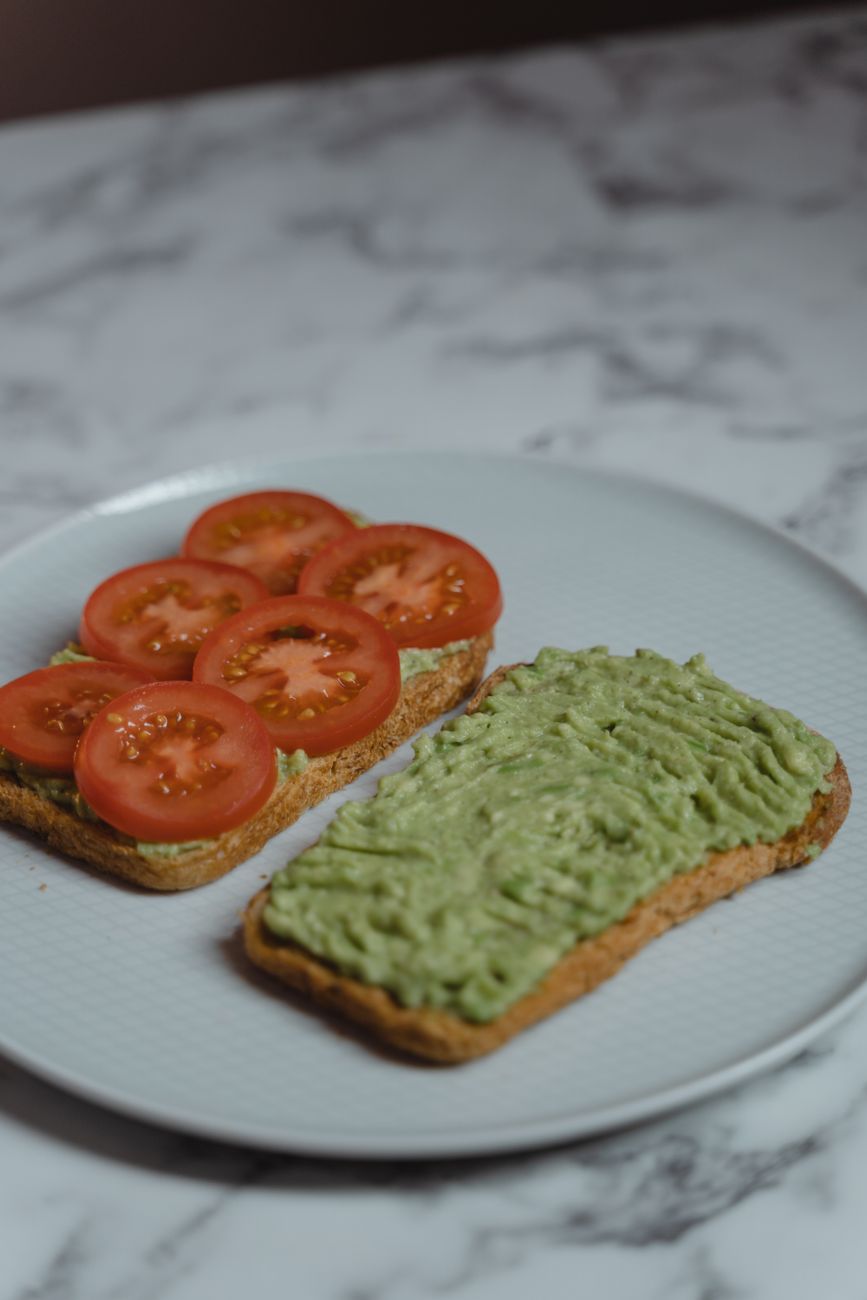 Sliced tomato and creamy avocado spread on toast, a healthy sandwich option