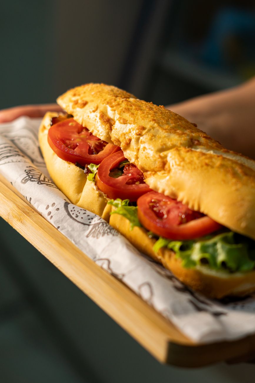 A fresh baguette sandwich with layers of tomato and lettuce