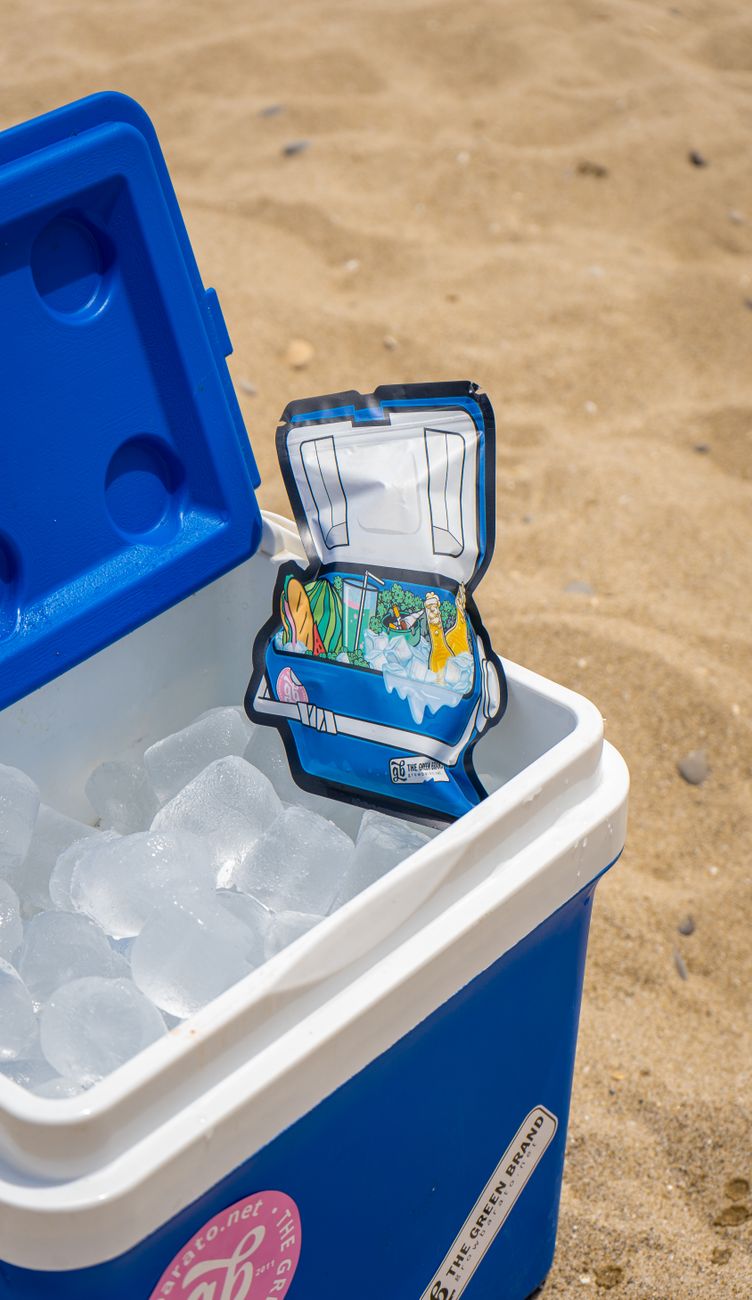 A blue cooler filled with ice sits open on a sandy beach