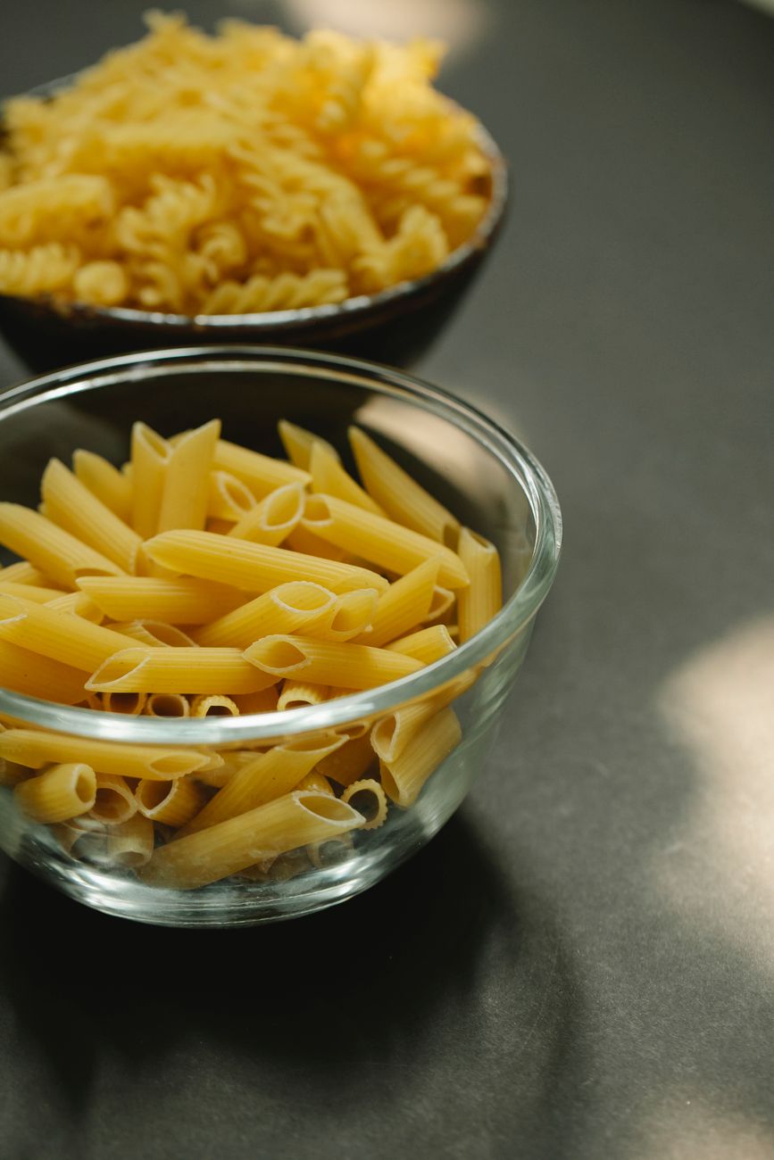 Bowls of raw pasta shapes displayed on a table