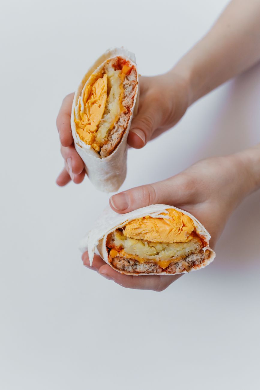 Two halves of a breakfast burrito filled with scrambled eggs and potatoes