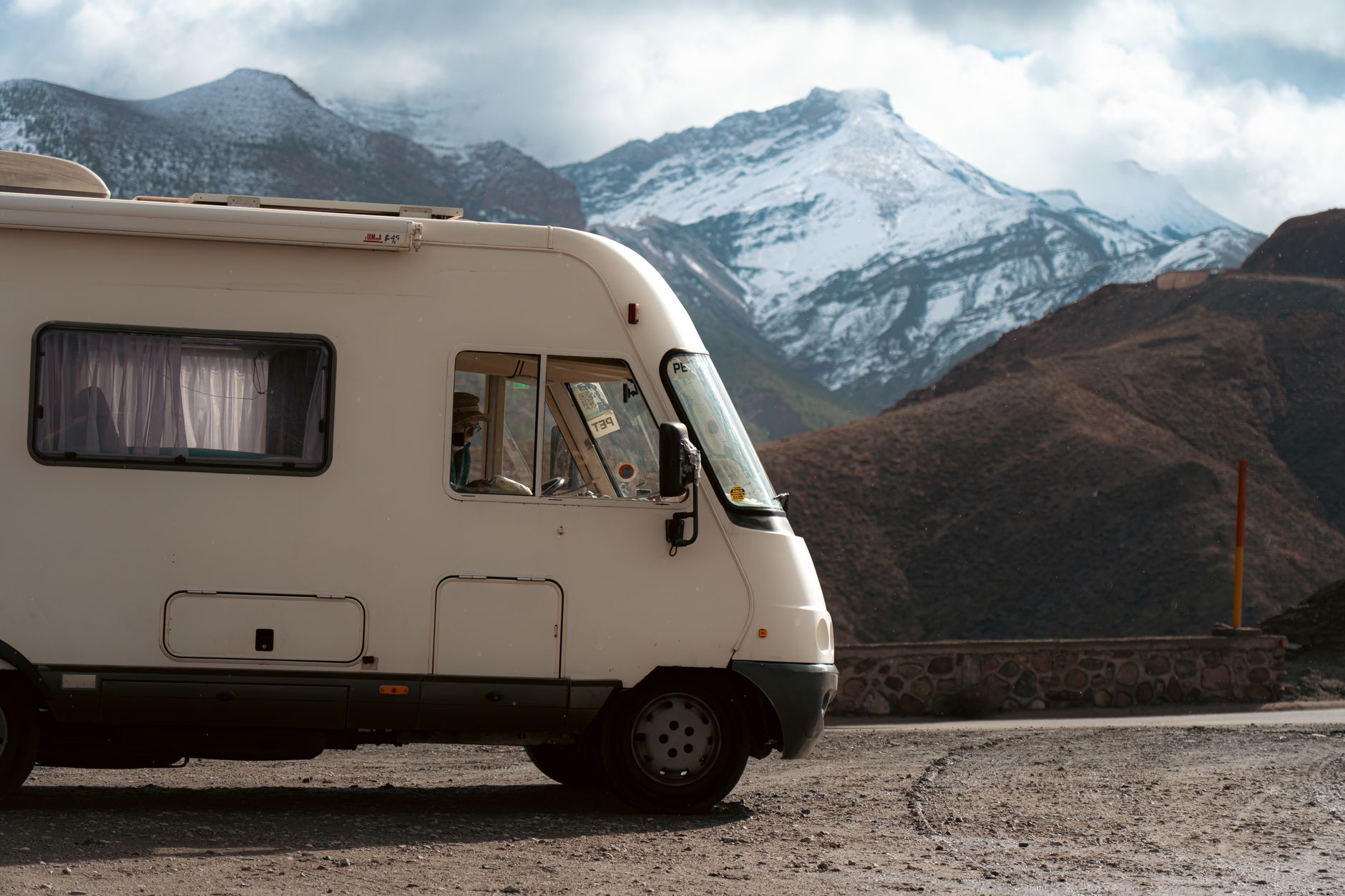Camper van parked on a road with snow-capped mountains in the background