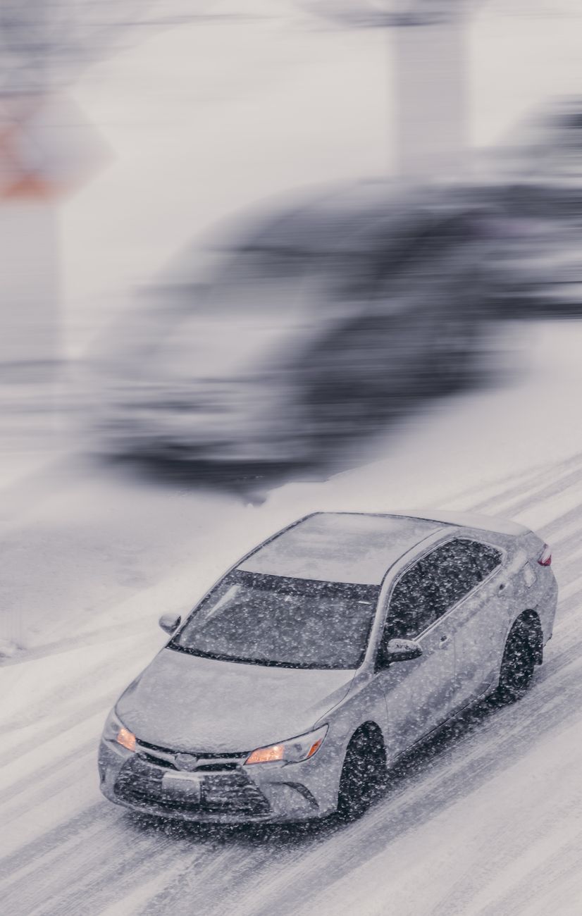 Car driving through a heavy snowstorm on an icy street