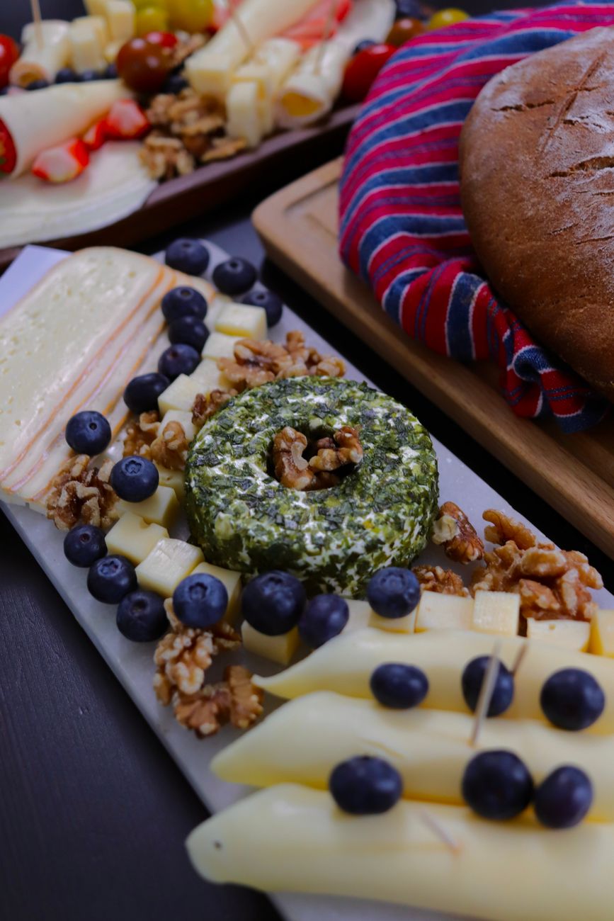 A vibrant cheese platter featuring various cheeses, fresh berries, and nuts