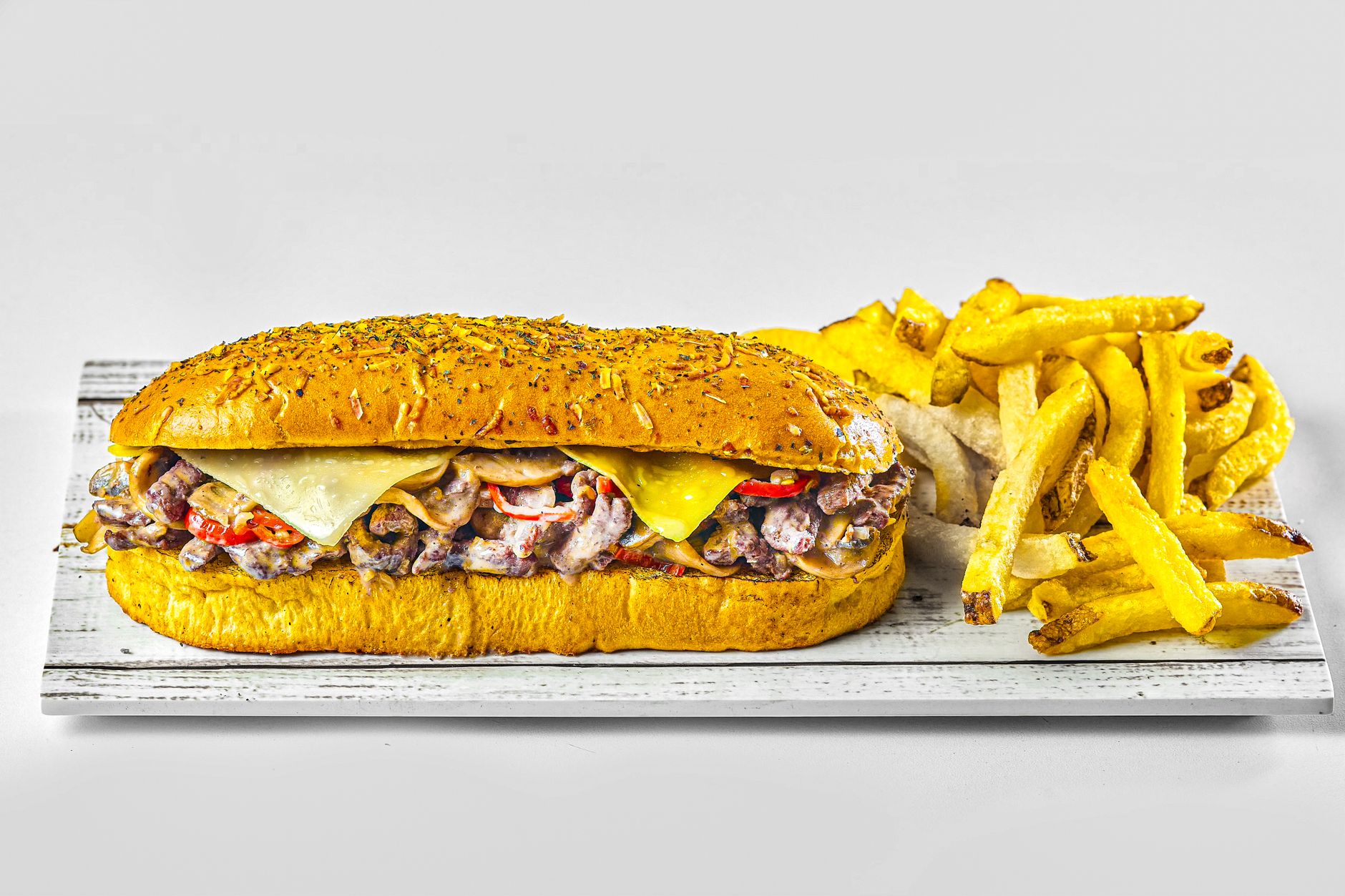 A cheesesteak sandwich served with crispy seasoned fries