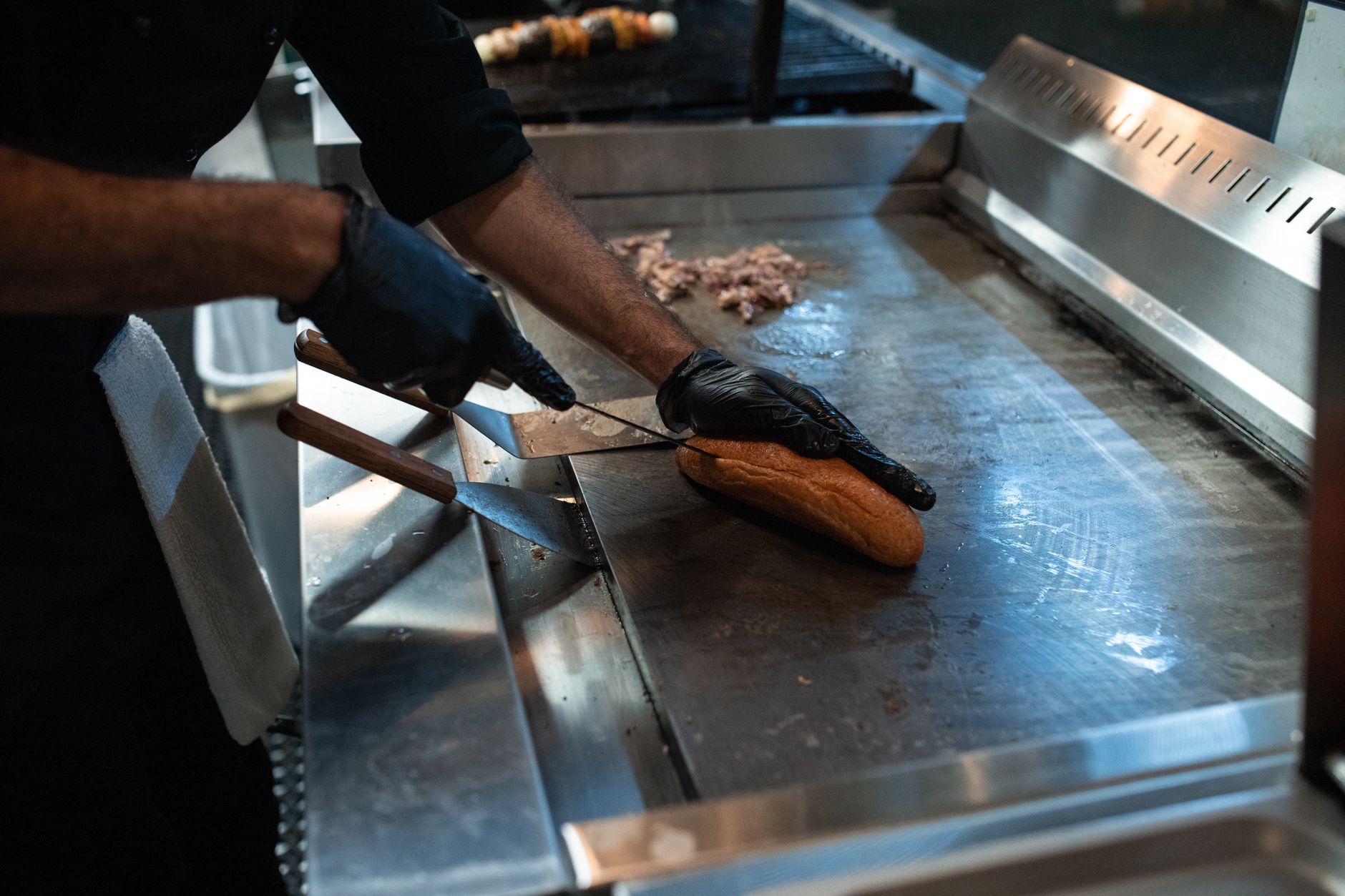 A chef slicing bread on the grill, preparing a sandwich in a professional kitchen