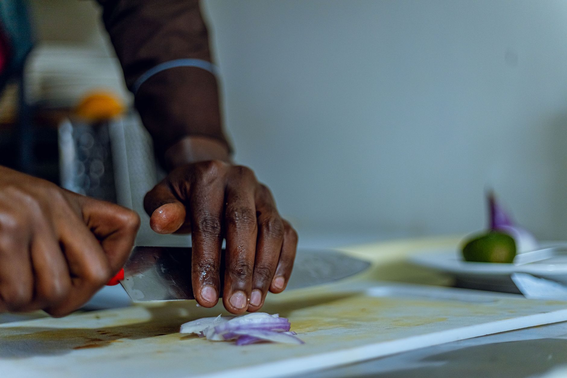 Chef slicing a red onion on a cutting board with fresh ingredients