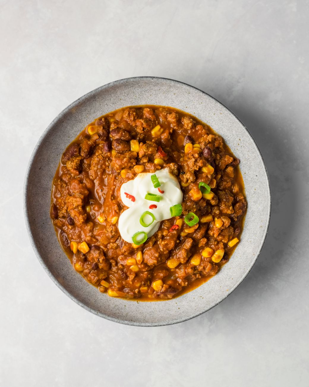 Delicious chili con carne with beans, corn, and a sour cream garnish