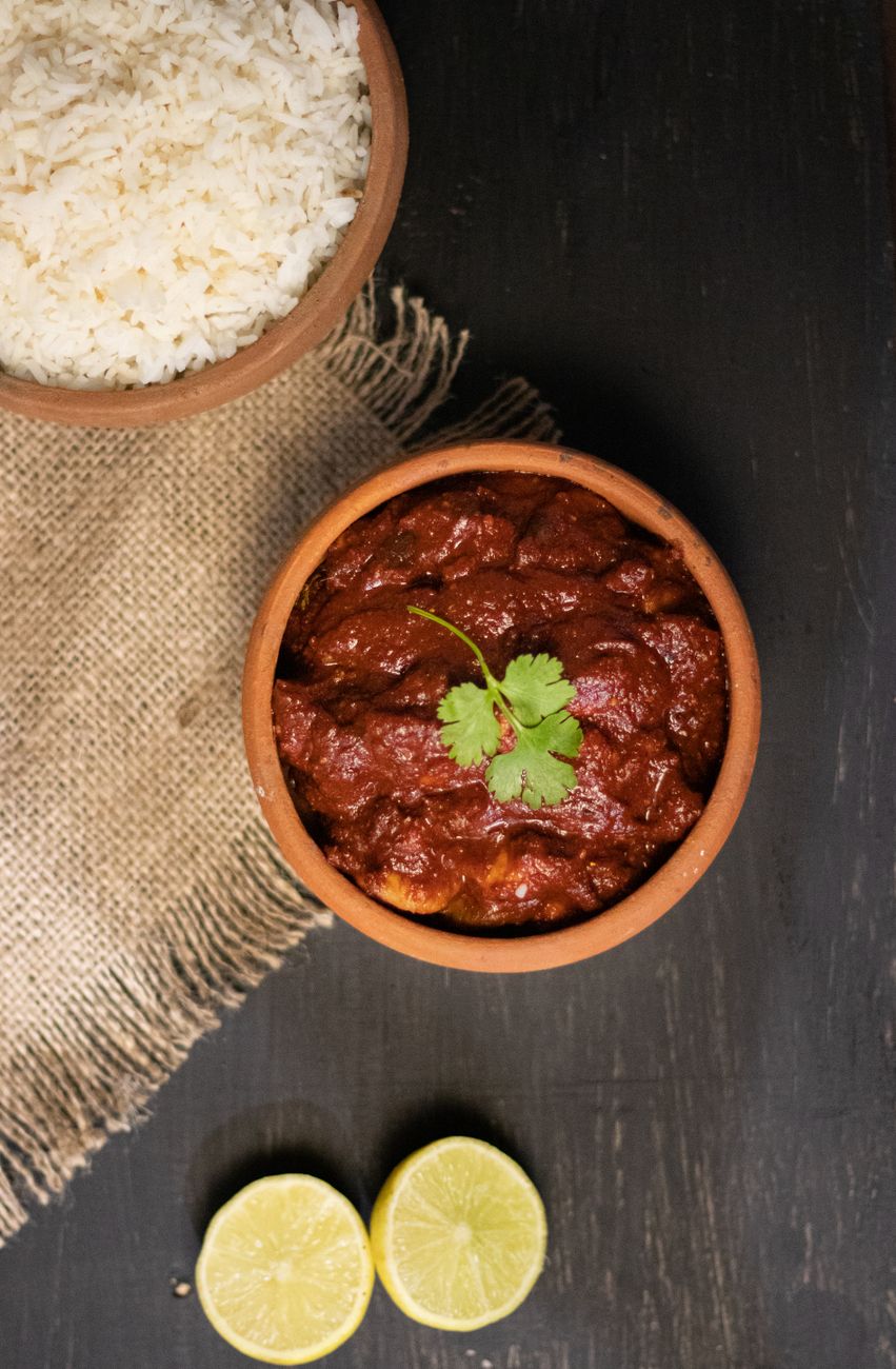 A top view of chili con carne served with rice and lime wedges