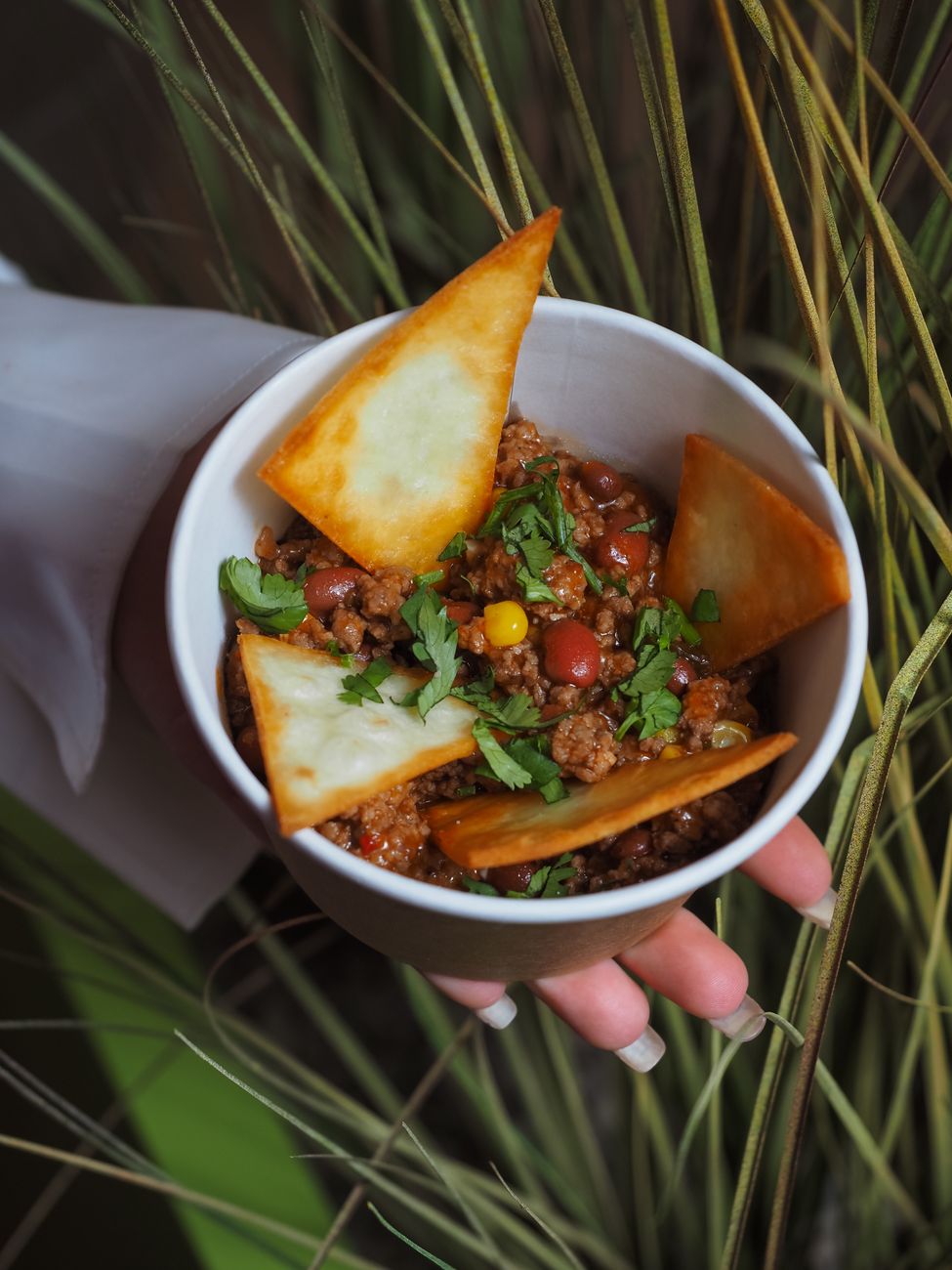 A bowl of chili con carne topped with crispy tortilla chips