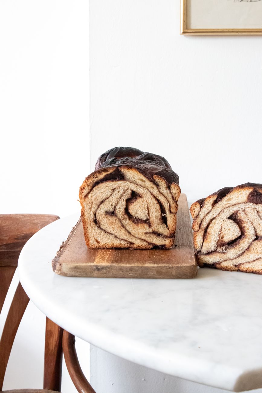 Close-up of a freshly baked chocolate swirl bread loaf on a rustic cutting board