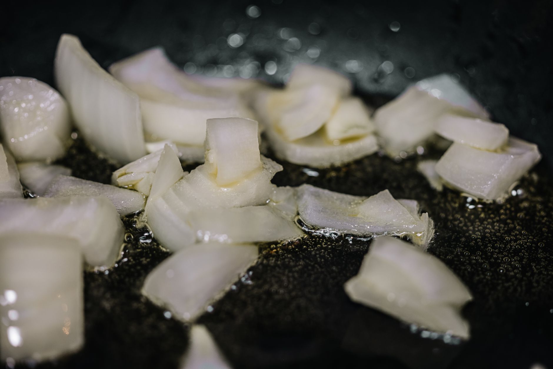 Close-up of chopped onions sizzling in oil in a frying pan