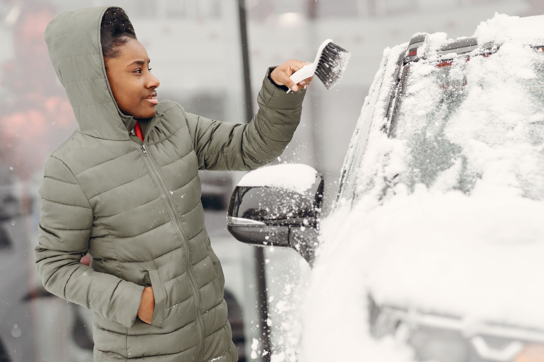 A person removes snow from a car during winter