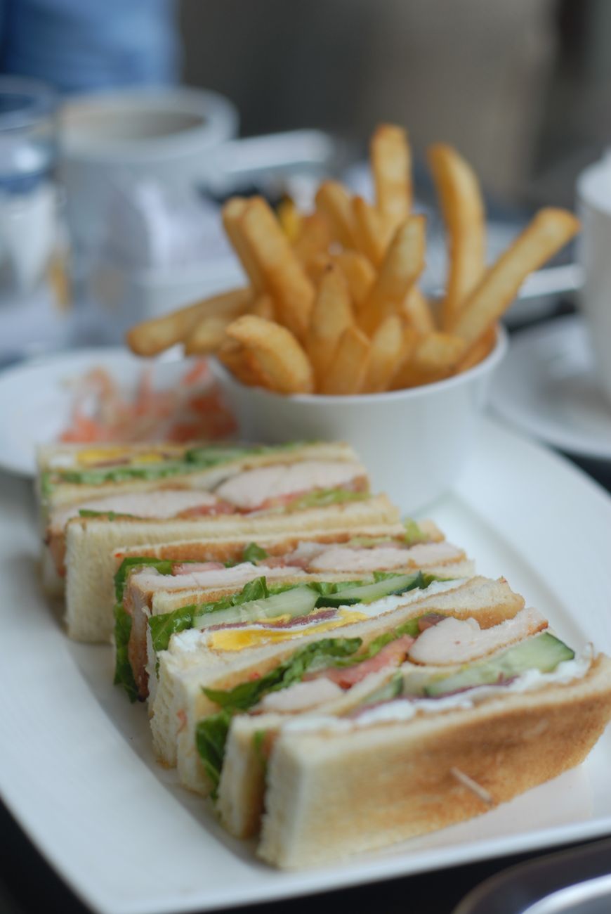 A close-up of a club sandwich paired with golden french fries
