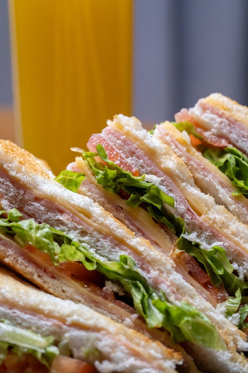Close-up of a club sandwich with layers of ham, lettuce, tomato, and cheese