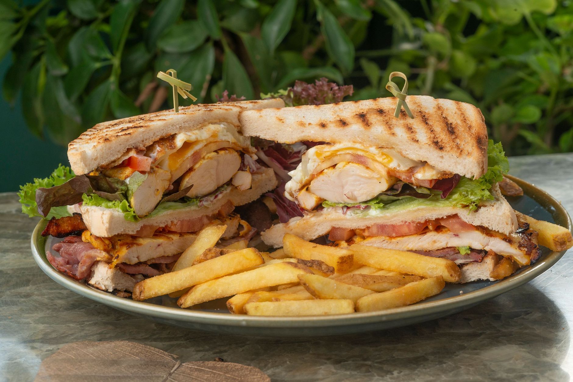 Appetizing club sandwich with fresh lettuce, tomatoes, and fries