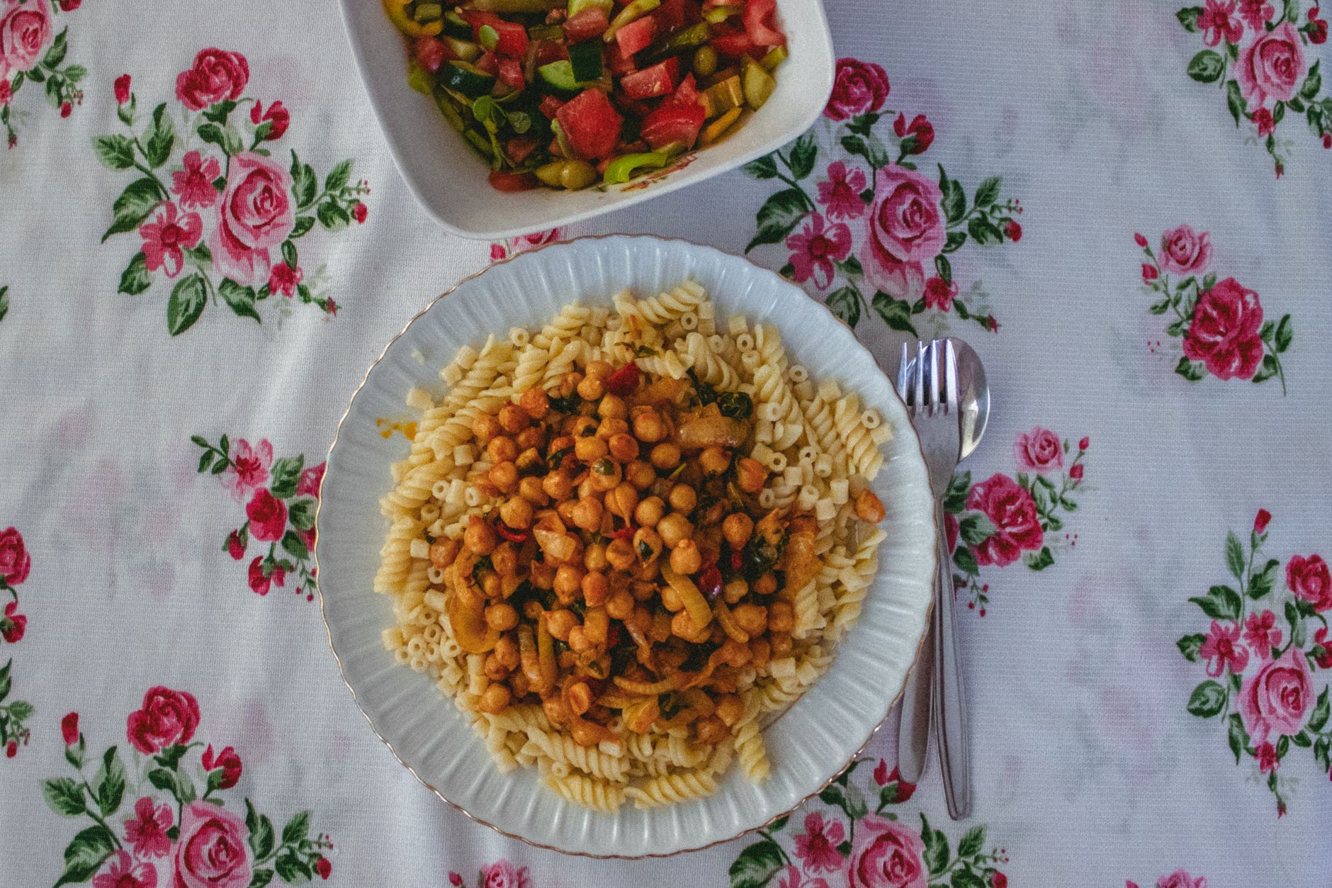 A colorful pasta dish served alongside a fresh side salad