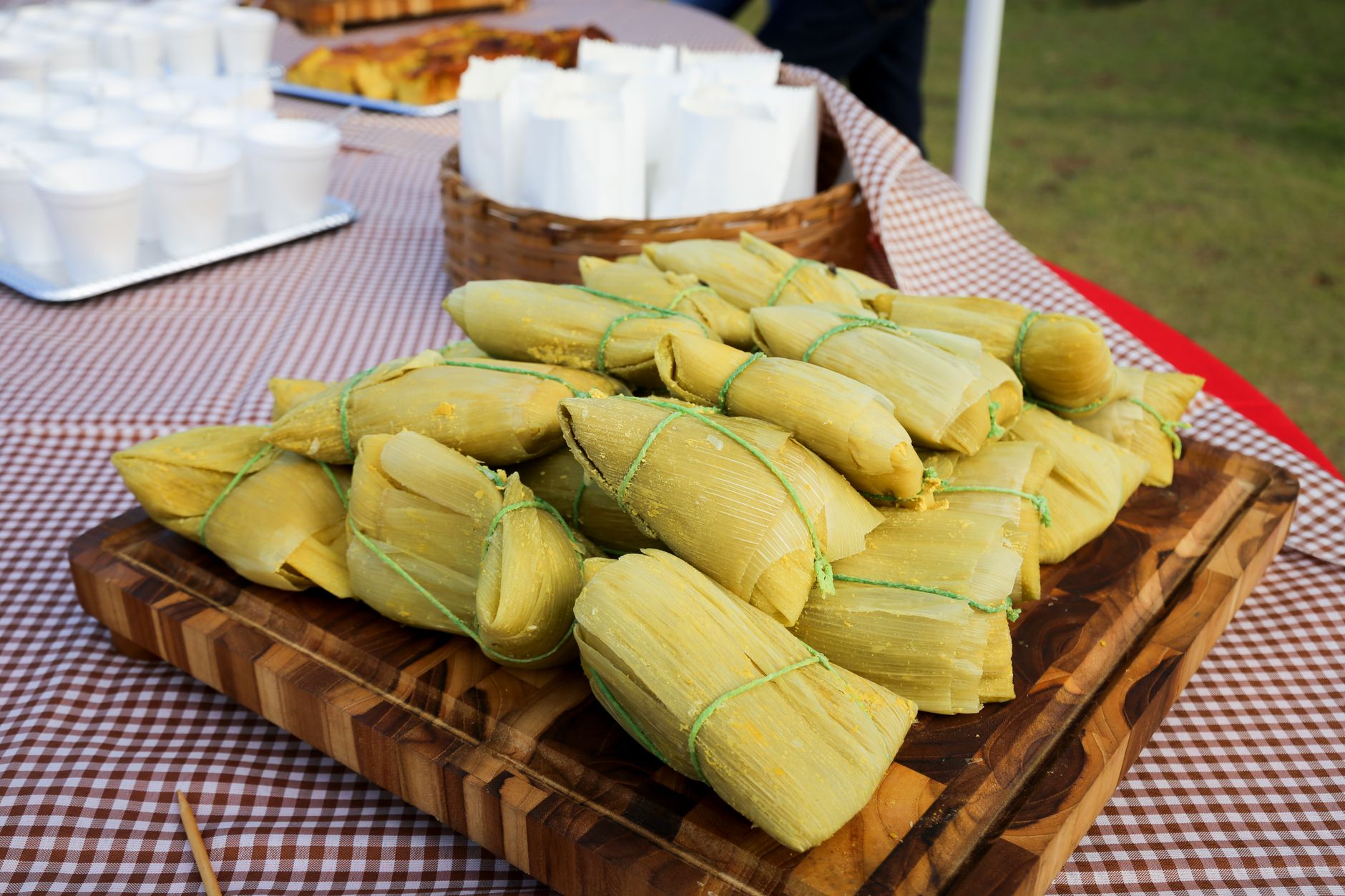 Corn husk-wrapped tamales on a wooden tray