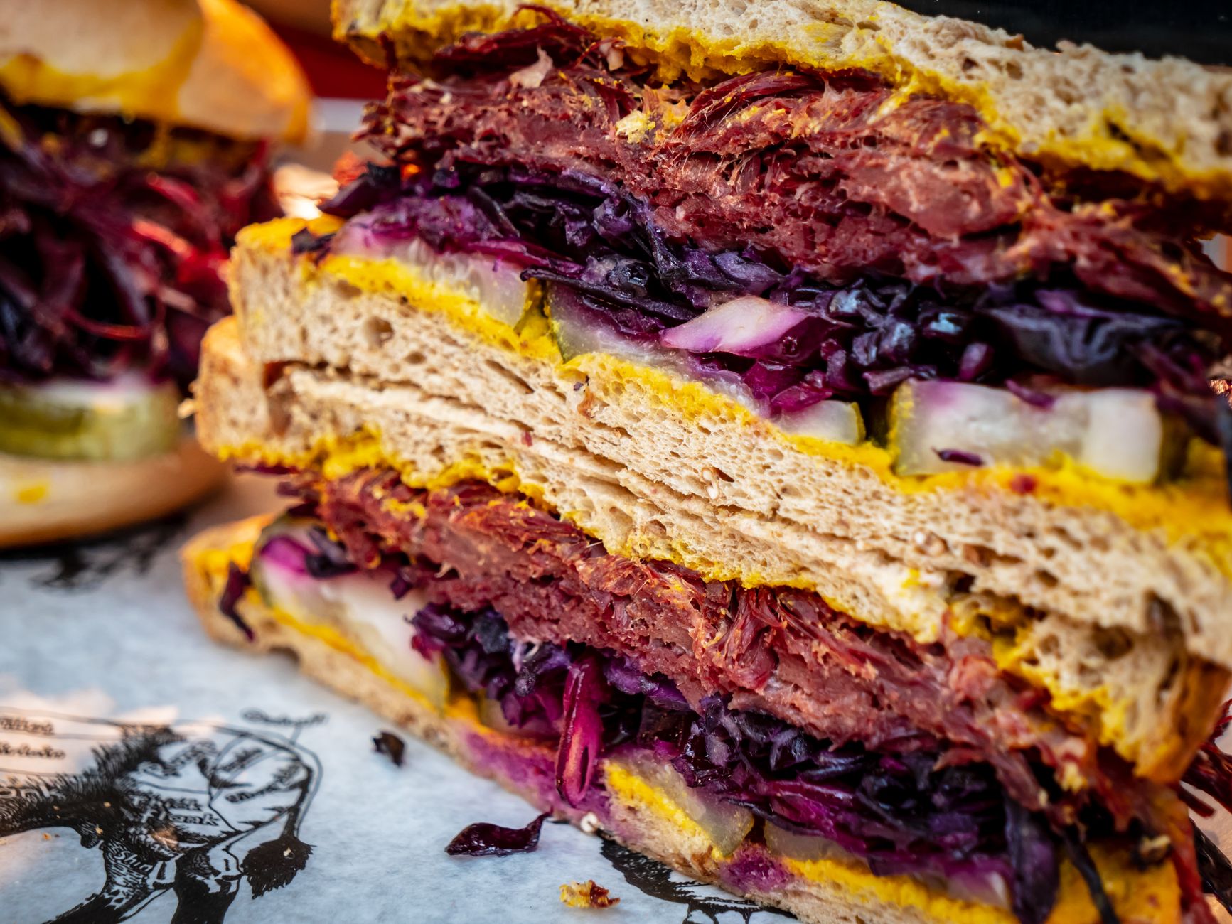 Sliced corned beef sandwich with mustard on rye bread