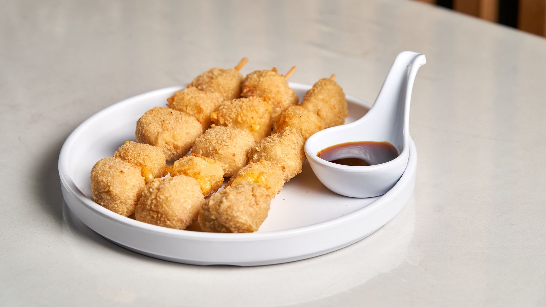 A plate of crispy cheese corn dogs served with soy dipping sauce