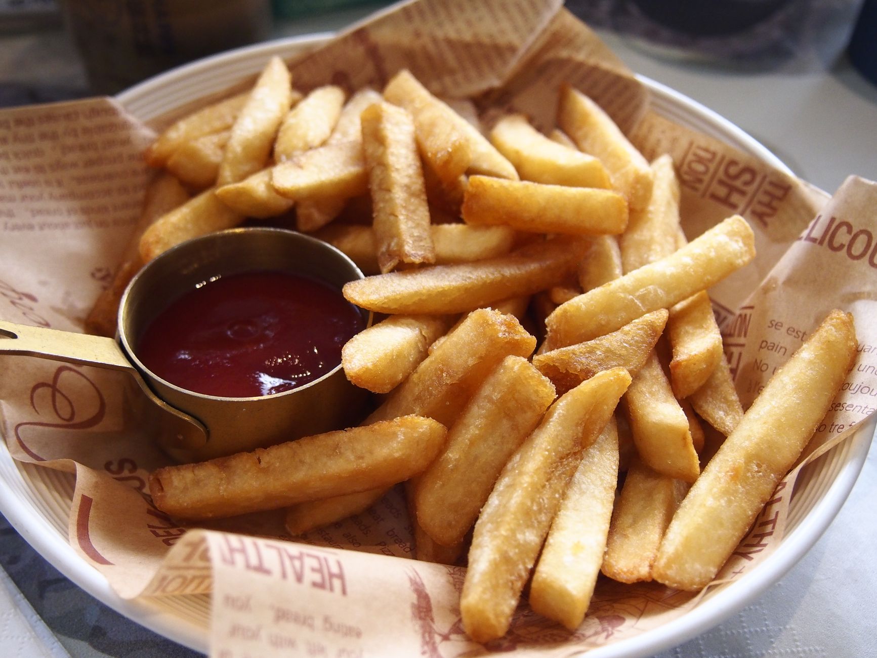 A plate of golden, crispy French fries served with a side of ketchup