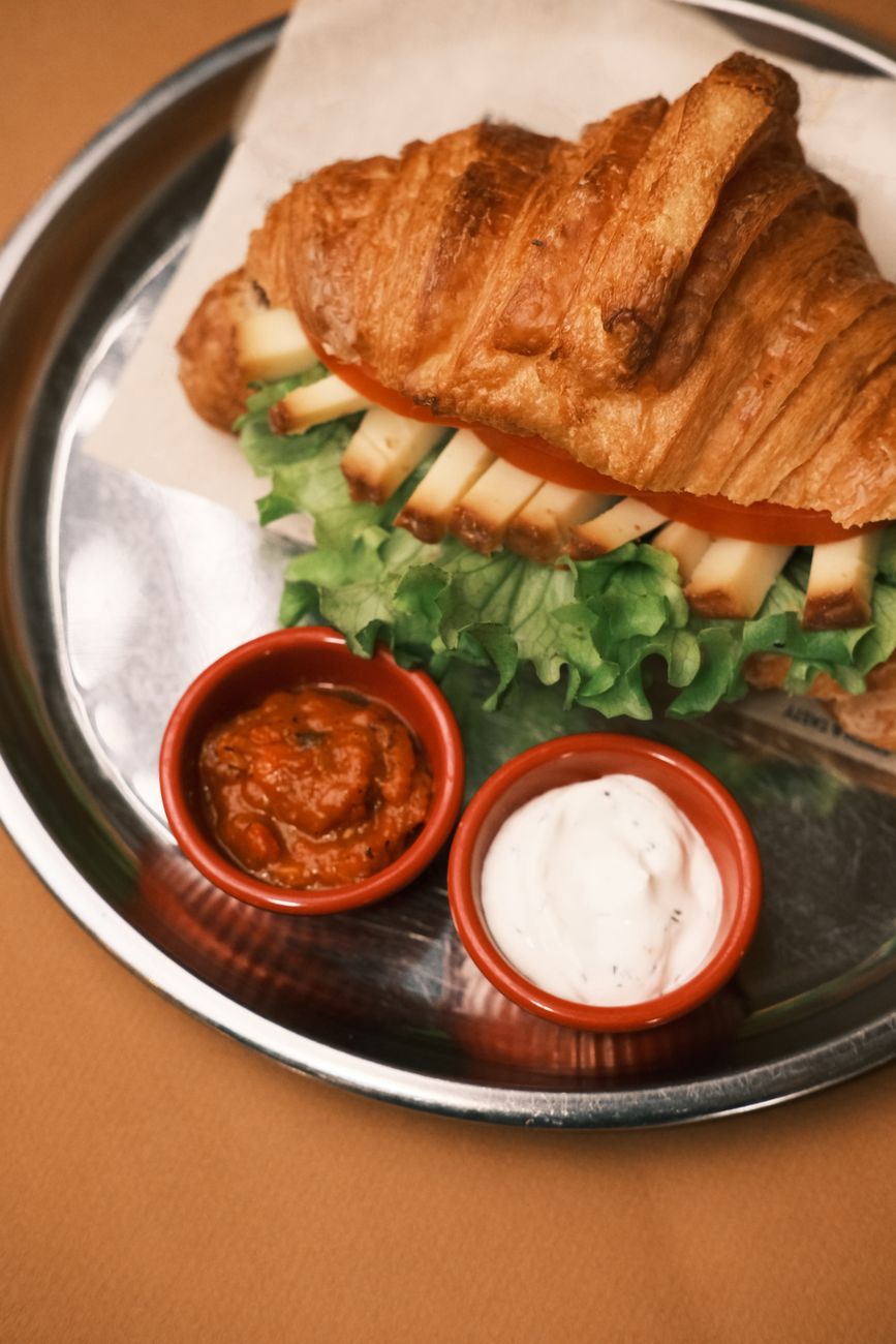 A delicious croissant sandwich served with a side of dipping sauce
