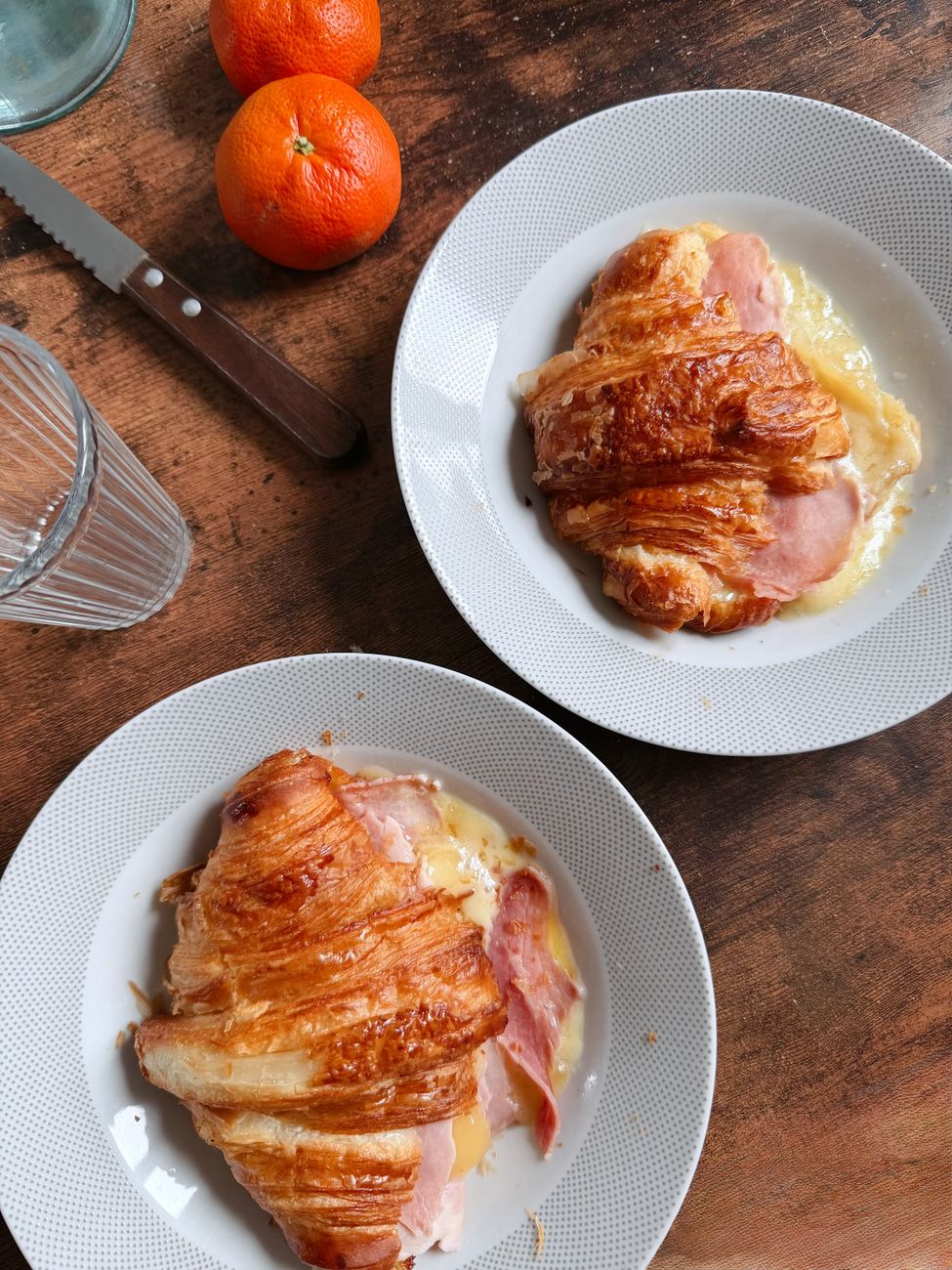 Two croissants filled with ham and melted cheese on plates