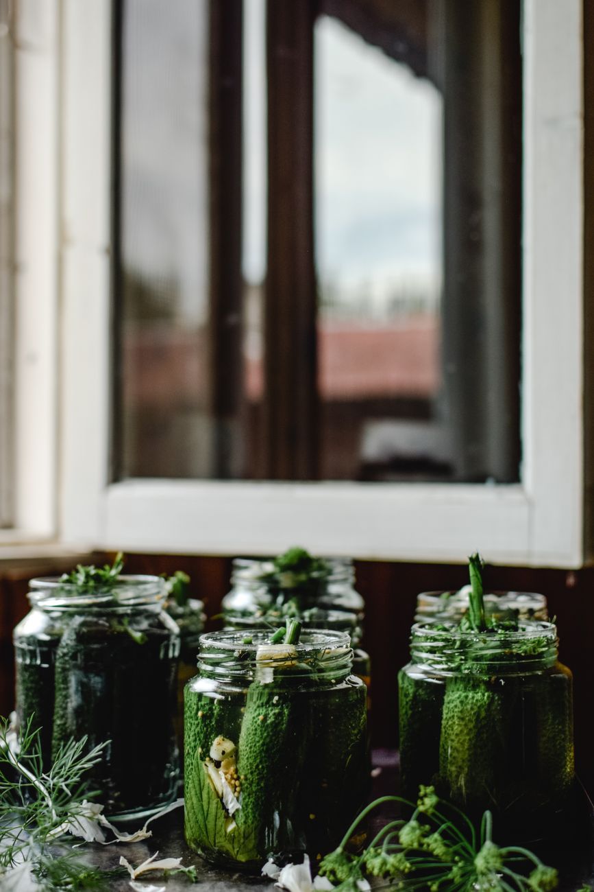 Fresh cucumbers pickling in glass jars on a wooden surface