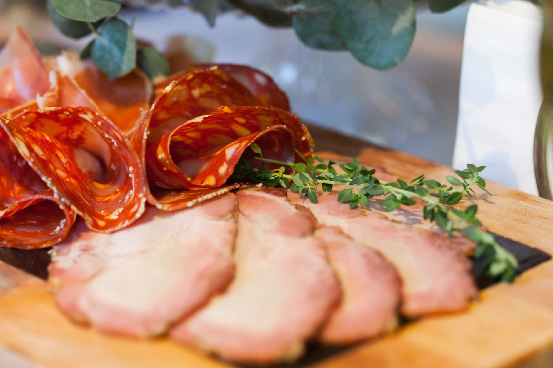 A delicious assortment of cured meats and fresh herbs on a wooden board