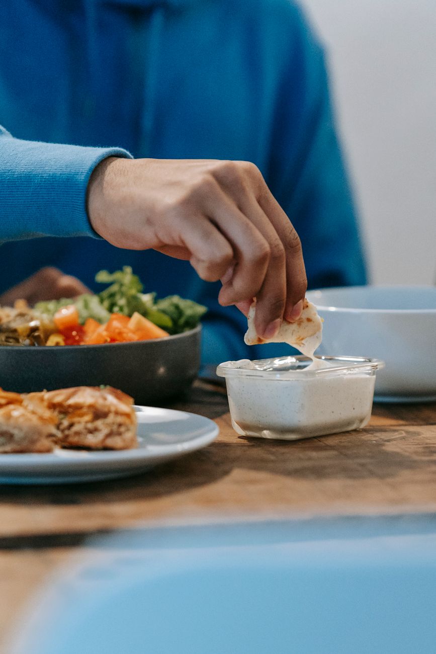 A person dipping a piece of flatbread into a creamy sauce