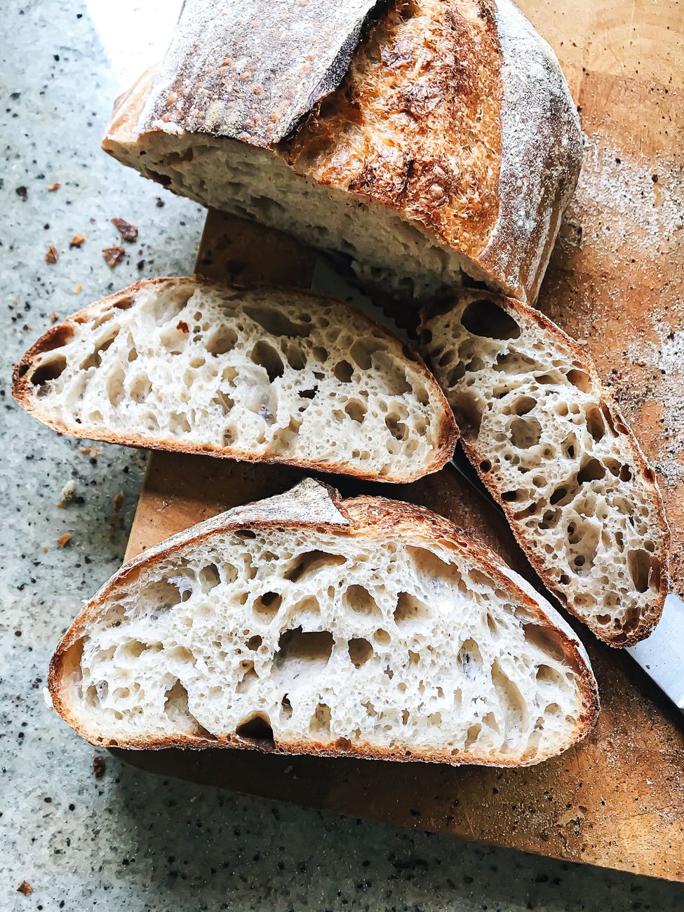 Freshly baked sourdough bread with an airy crumb, sliced on a cutting board