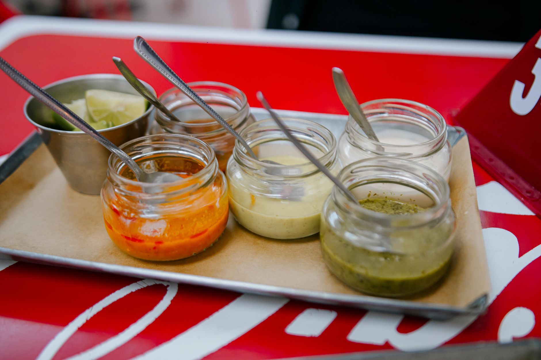 Clear glass jars filled with sauces arranged on a stainless steel tray