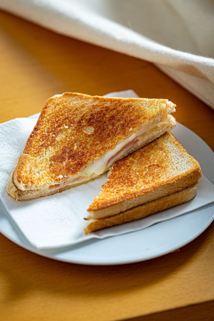 Golden brown grilled cheese sandwich on a white plate with napkin