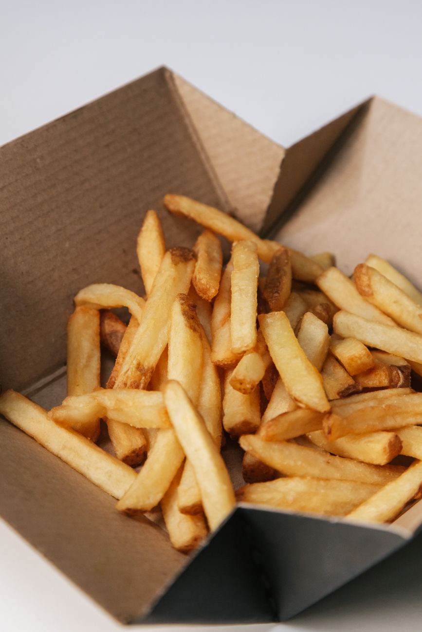 Close-up of golden french fries in a brown cardboard takeout box