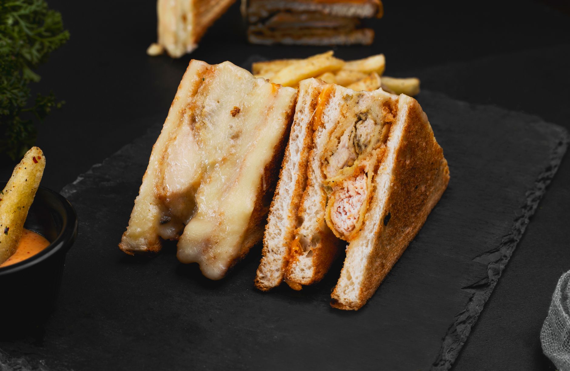 Close-up of a gourmet grilled club sandwich served with crispy fries