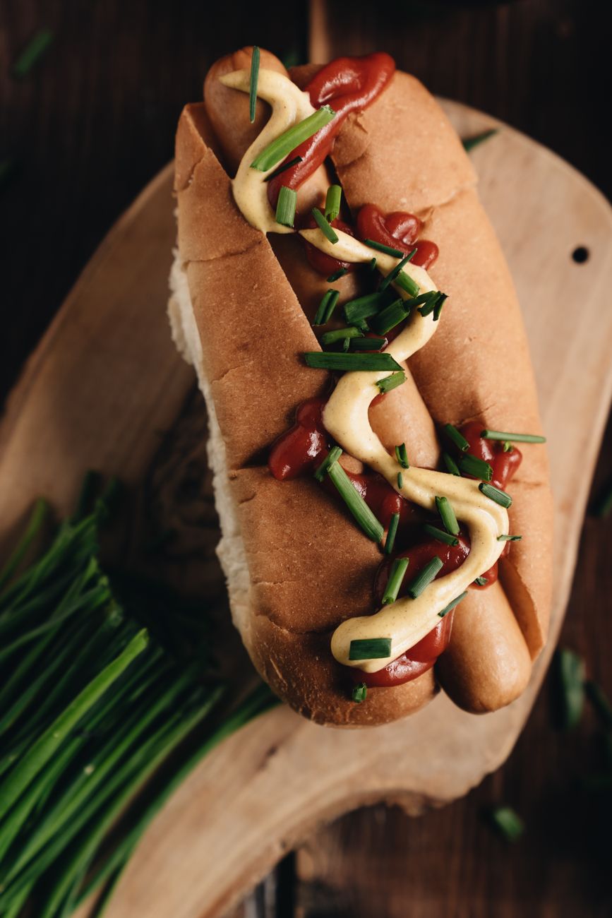 A delicious gourmet hot dog with mustard, ketchup, and green onions