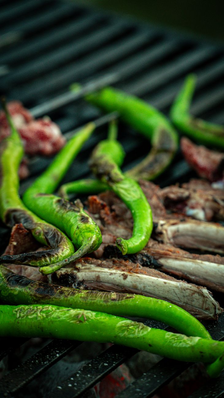 Close-up of green peppers and meat cooking on a grill
