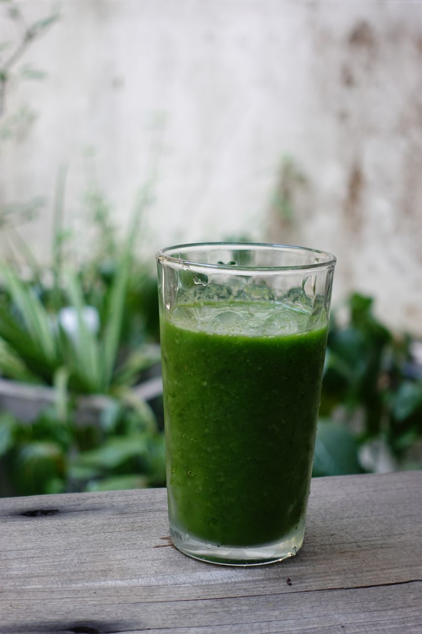 A vibrant green vegetable smoothie in a clear glass