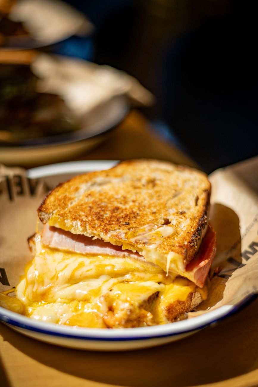 Mouthwatering grilled cheese sandwich with ham on a paper-wrapped plate
