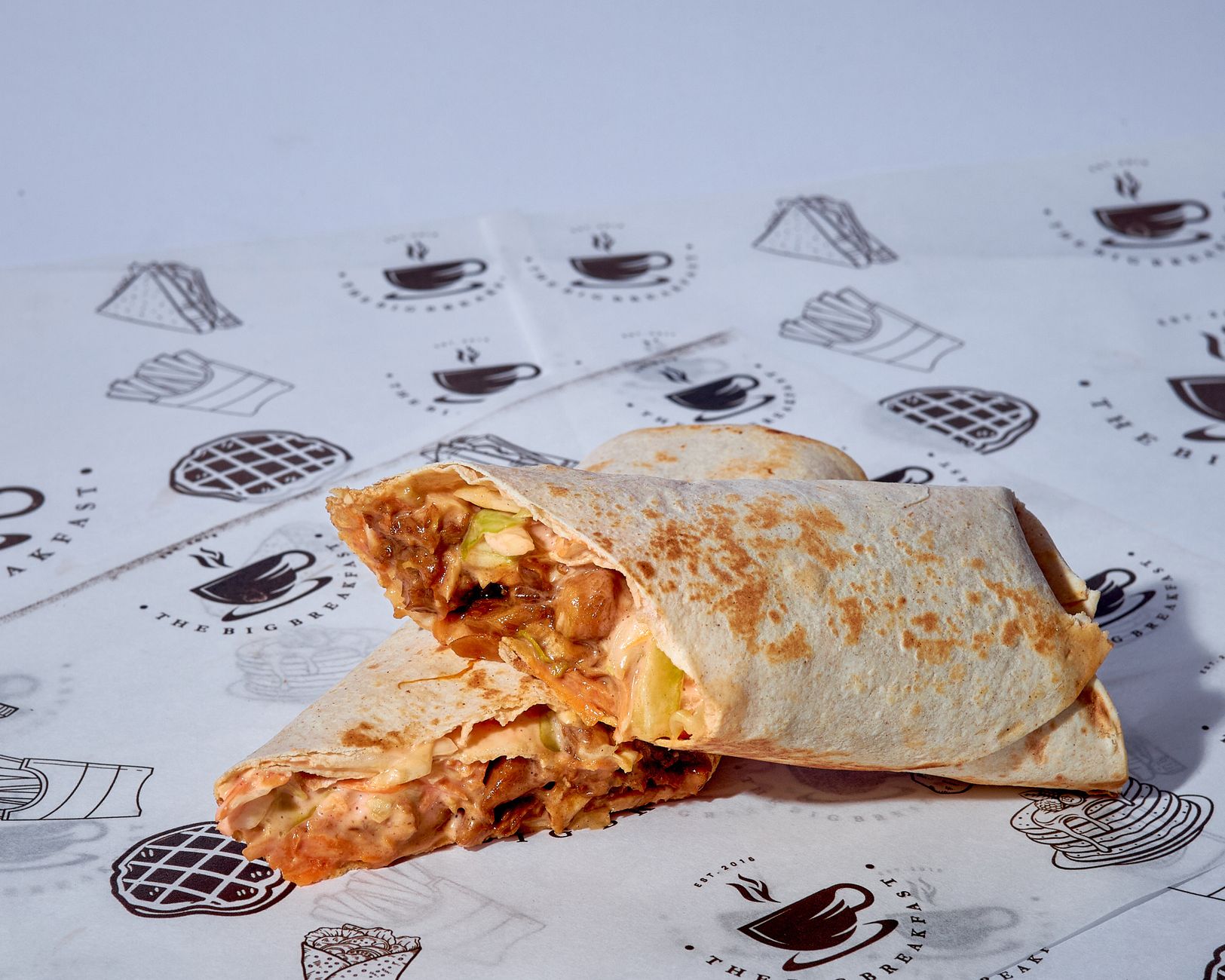 Close-up of a grilled chicken burrito with vegetables, sliced diagonally