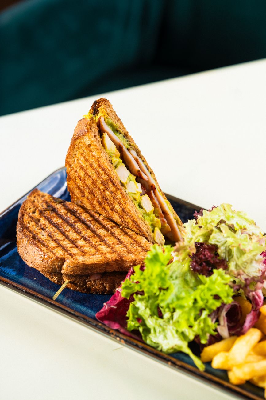 A grilled chicken sandwich served with a side of fresh salad