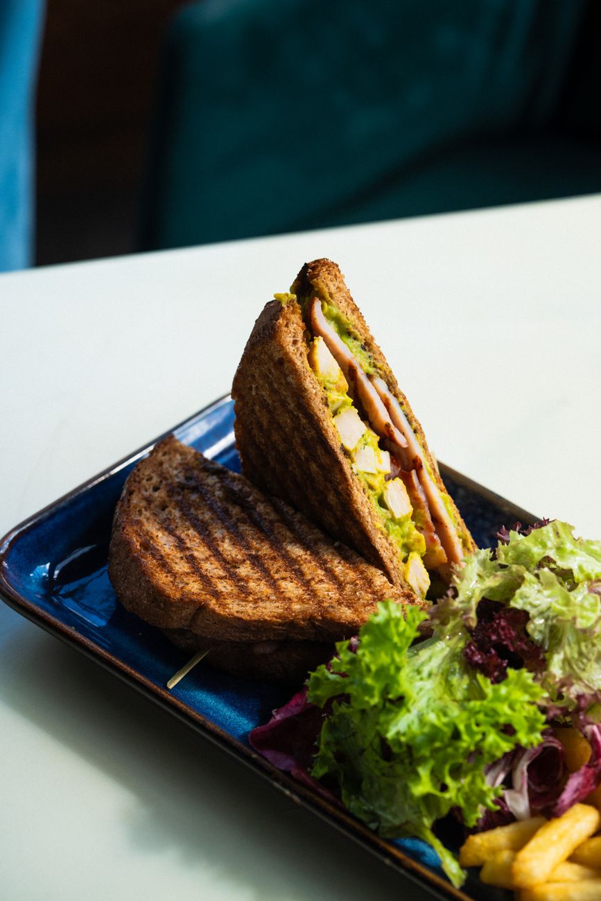 A grilled chicken sandwich plated with a fresh salad side