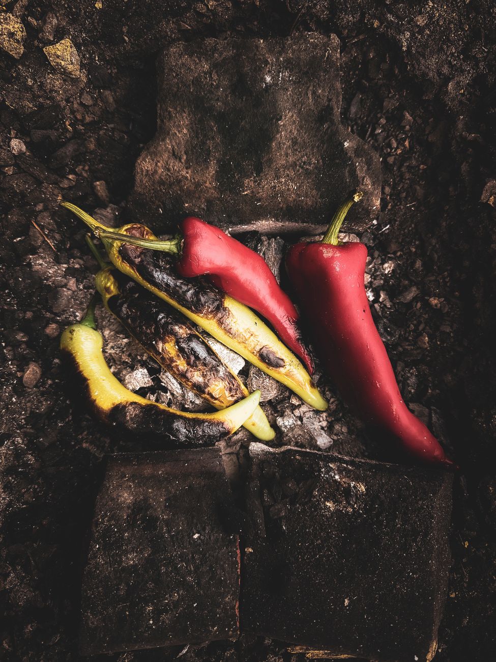 Close-up of grilled red and green peppers on a rustic charcoal surface
