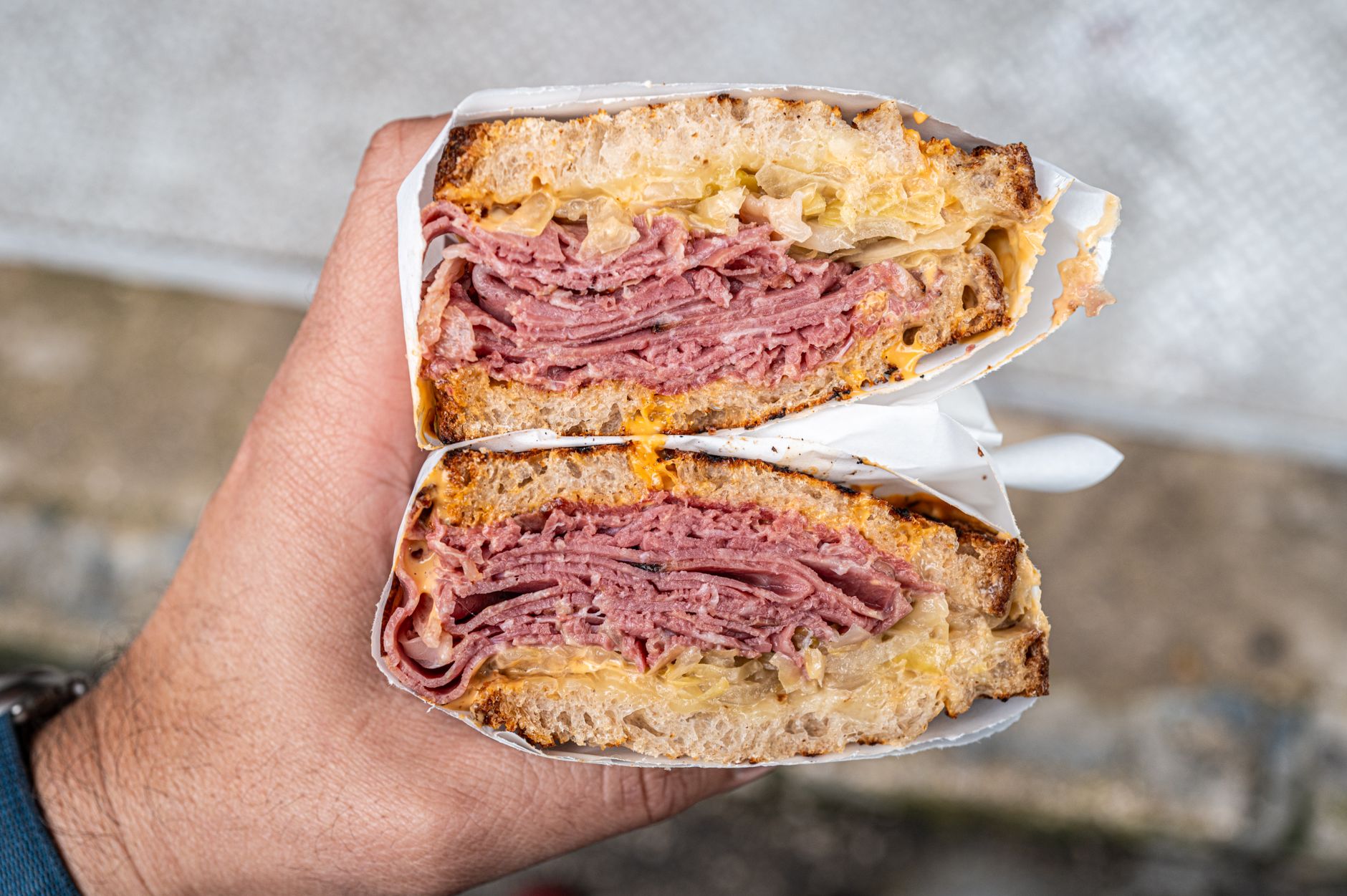 A grilled deli-style sandwich held close-up for a food presentation