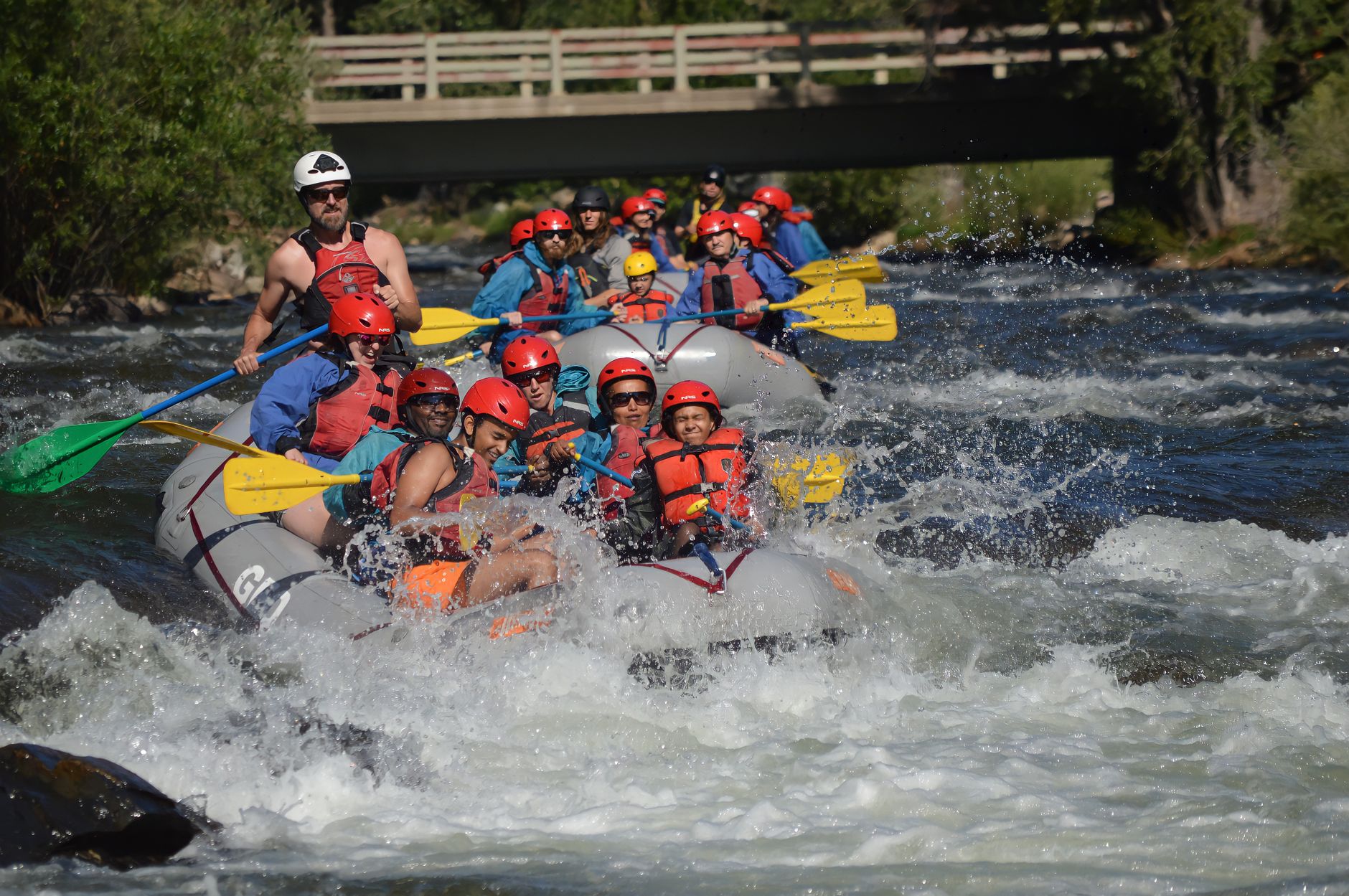 Group of people whitewater rafting with paddle splashes on a river